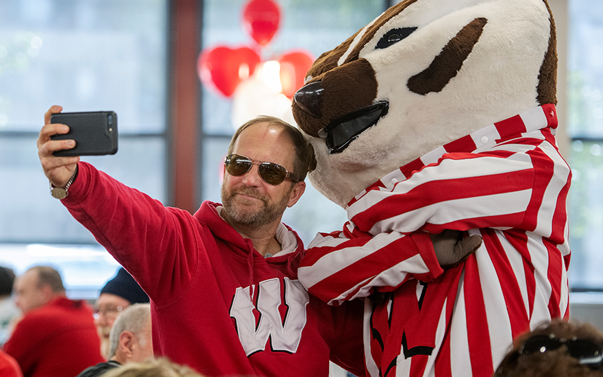 An alumnus posing for a selfie with Bucky Badger