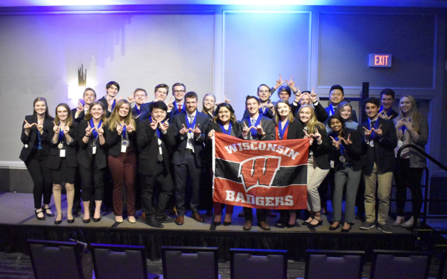 DECA regional competitors on stage holding UW-Madison flag DECA regional competitors on stage holding UW-Madison flag