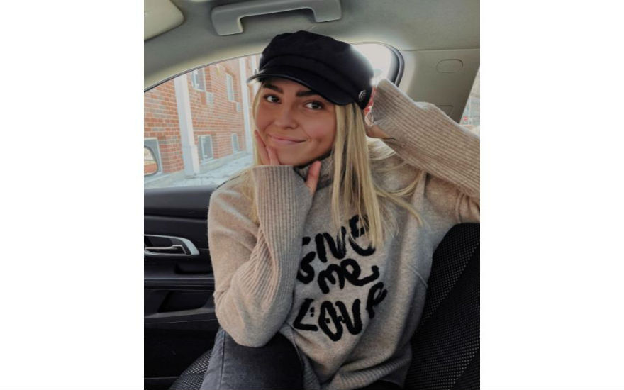 Jade is wearing a black hat with an oatmeal colored sweater that says "Give Me Love". Jade sits facing the camera in the passenger seat of a vehicle. Jade is wearing a black hat with an oatmeal colored sweater that says "Give Me Love". Jade sits facing the camera in the passenger seat of a vehicle.