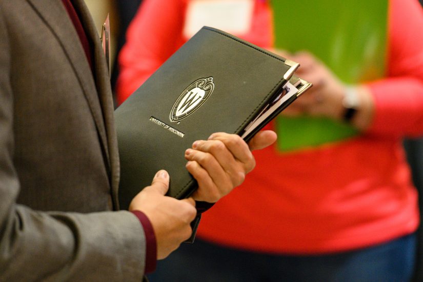 A man holding leather folder with UW crest on it