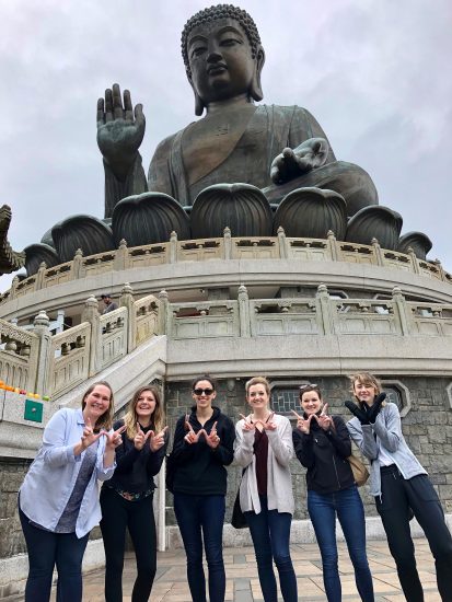 Carly with a group of people in front of a Buddha statue