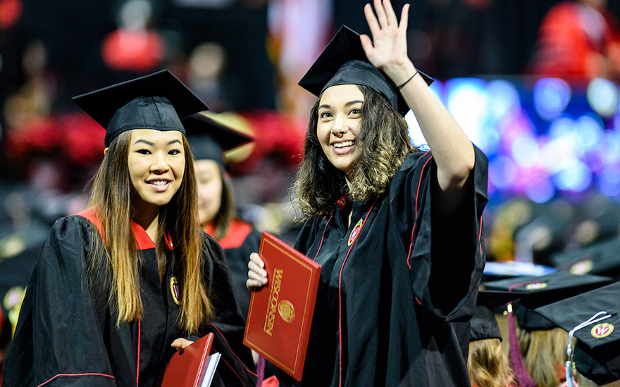 students in graduation caps and gowns, holding diplomas students in graduation caps and gowns, holding diplomas