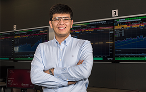Ph.D. student Bekhzod Khoshimov stands in WSB's Finance Lab for a portrait