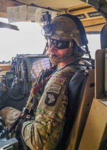 A man looks to the camera aboard a military vehicle