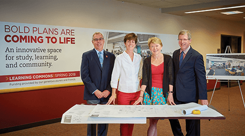 Dean Massey, Ed Van Gemert, Sarah Mangelsdorf, and Steve Cramer standing over blueprints