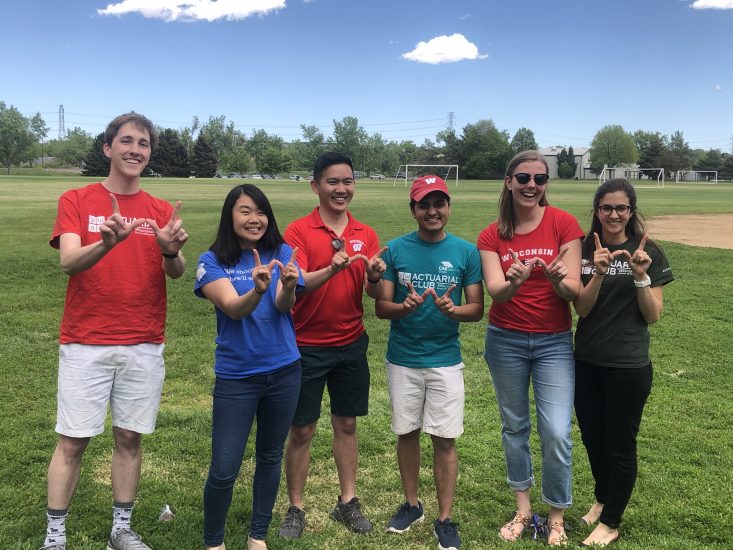 Lakch stands with hands in a W shape with five Badger interns